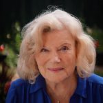Headshot of a lady with grey hair and a blue blouse.